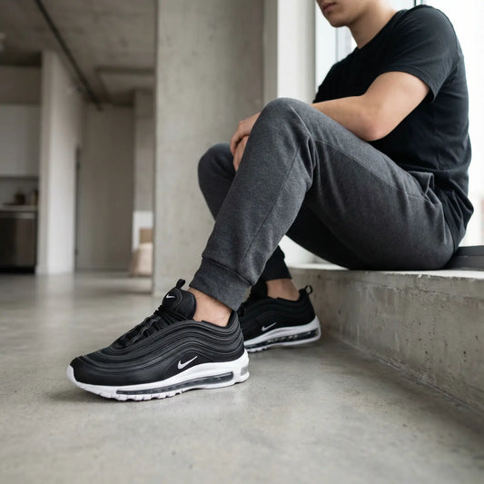 Person wearing black Nike sneakers sitting on a concrete ledge.