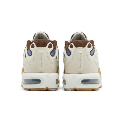 Pair of beige sneakers with brown and blue accents on a white background