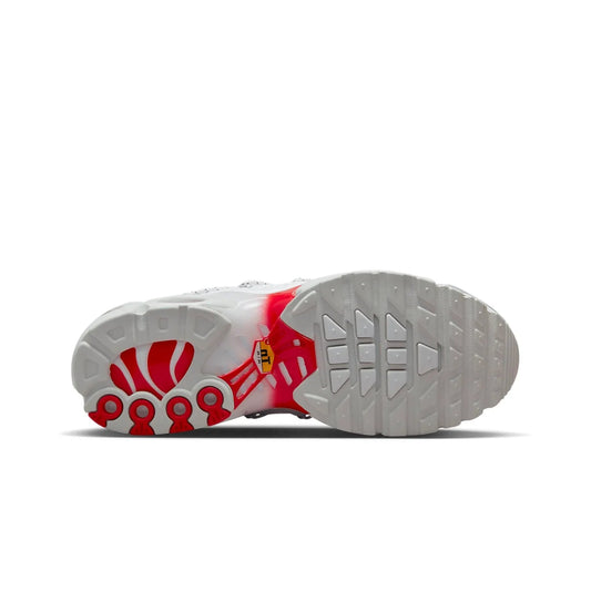 Sole of a white shoe with red accents on a white background