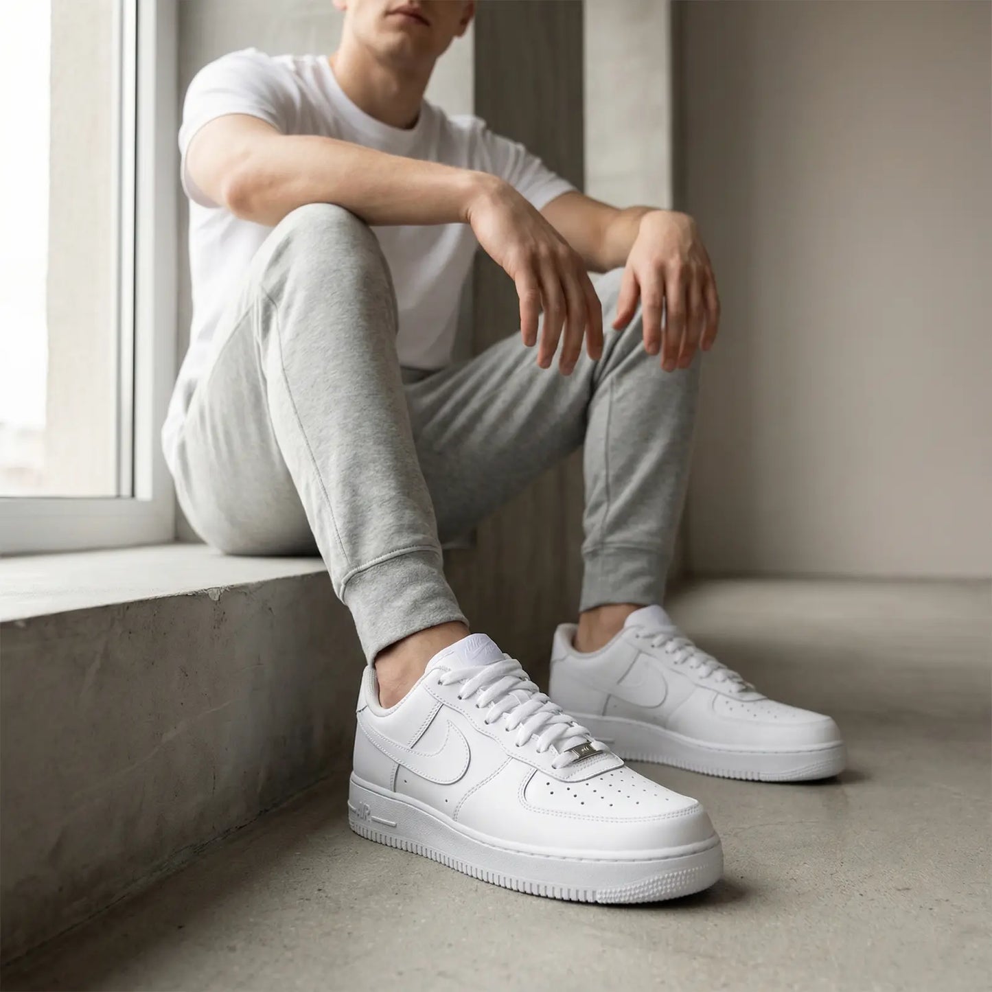 Person wearing white sneakers sitting by a window